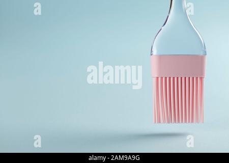 Brosse de cuisson en silicone rose avec poignée transparente avec espace de copie sur fond bleu Banque D'Images