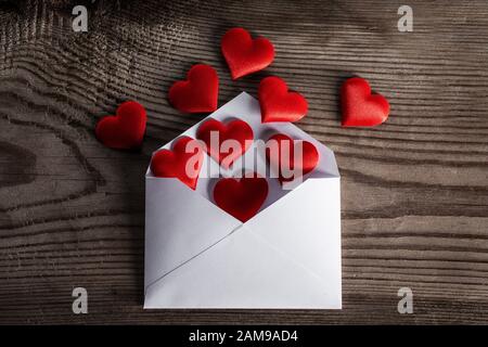 Lettre d'amour de Saint-Valentin, enveloppe avec coeur rouge tas propagation sur fond de bois. Banque D'Images