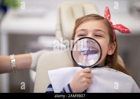 Jolie fille montrant son grand sourire sous une loupe Banque D'Images
