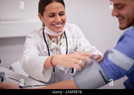 Jeune homme ayant vérifié sa tension artérielle dans le cabinet du médecin Banque D'Images