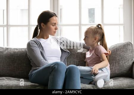 Une mère sérieuse parle avec une petite fille dans le salon Banque D'Images