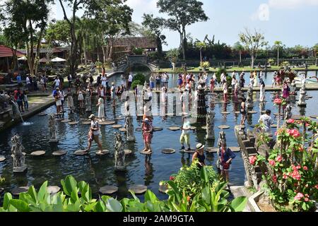 Les touristes marchant une pose sur des marches en pierre dans l'une des piscines parmi la verdure dans le palais d'eau de Tirta Gangga à Bali. Banque D'Images