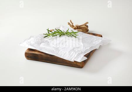 Feuille de cire blanche froissée et de romarin frais sur la planche à découper Banque D'Images