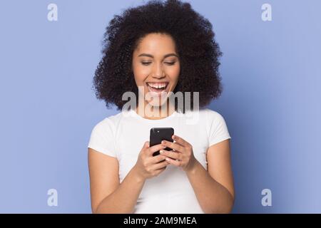 Enchantée heureuse dame afro-américaine du millénaire tenant le téléphone mobile. Banque D'Images