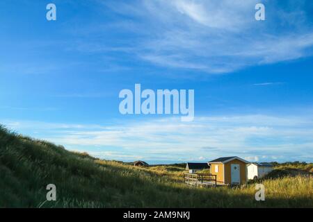 Les cottages traditionnels colorés en bois de loisirs au bord de la côte de la mer en Suède, cachés derrière les dunes. Banque D'Images