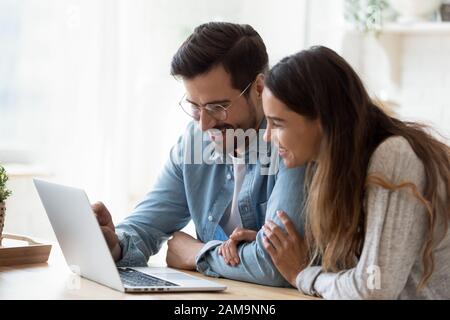 Heureux jeune couple mixte de course regarder des vidéos drôles sur l'ordinateur. Banque D'Images