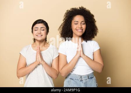 Fidèles amis multiculturels de femmes priant pour bonne chance. Banque D'Images