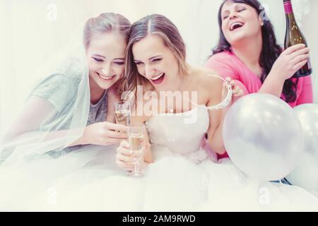 Mariée et bridesmaids se moquant et buvant tout en achetant la robe de mariage Banque D'Images