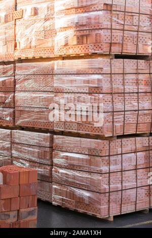 Plusieurs palettes de briques de béton empilés les uns sur les autres en dépôt. La production industrielle de briques. photo verticale. Banque D'Images