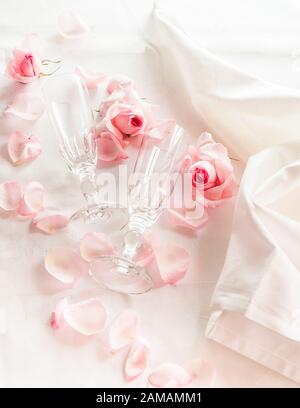 Verres à champagne en cristal de mariage sur une serviette en satin avec une bouteille de champagne et des pétales de rose Banque D'Images