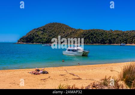 Relaxing sur la plage près d'un bateau-taxi au parc national d'Abel Tasman, Nouvelle-Zélande Banque D'Images