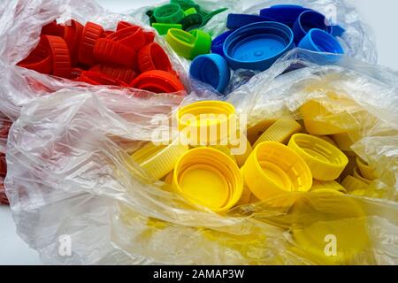 Bouchons en plastique colorés triés par couleurs dans des sacs en plastique transparents à usage unique. PP pollution PET. Solutions de recyclage pour déchets plastiques. Banque D'Images