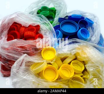 Bouchons en plastique colorés triés par couleurs dans des sacs en plastique transparents à usage unique. PP pollution PET. Solutions de recyclage pour déchets plastiques. Haut Banque D'Images