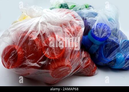 Bouchons en plastique colorés triés par couleurs dans des sacs en plastique transparents à usage unique. PP pollution PET. Solutions de recyclage pour déchets plastiques. Banque D'Images