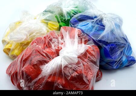 Bouchons en plastique colorés triés par couleurs dans des sacs en plastique transparents à usage unique. PP pollution PET. Solutions de recyclage pour déchets plastiques. Banque D'Images