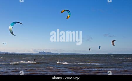 Longniddry, East Lothian, Scotland, UK. 12Th Jan, 2020. Après une journée d'hier sont très humides, ces kite surfeurs étaient heureux de voir le soleil hiver et se sentir un vent WSW pour leur permettre d'obtenir leurs cerfs-volants colorés dans l'Estuaire de Forth avec la ville d'Édimbourg, dans l'arrière-plan. Banque D'Images