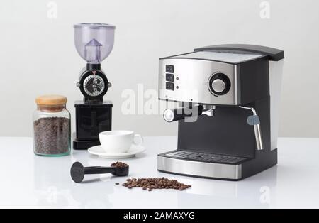 cafetière avec mixeur et grain de café sur la table blanche Banque D'Images