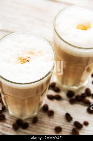 Deux verres de café latte et les grains de café sur une vieille table en bois Banque D'Images