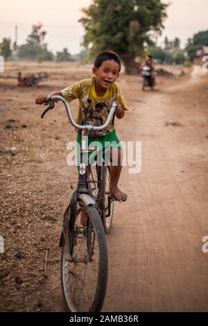 Don DET, LAOS - 5 AVRIL 2013 : un jeune garçon non identifié fait un tour à vélo dans le village de Don Det, Laos. Banque D'Images