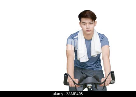 Installer un jeune homme à l'aide d'un vélo d'exercice isolé sur fond blanc, sport et concept sain Banque D'Images