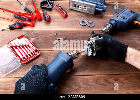 Le maître à réparer un appareil électrique cassée : perceuse, cutter sur une table en bois. Atelier de réparation d'outils électriques Banque D'Images