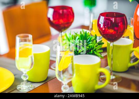 Gros plan de vaisselle sur la table. Plaques jaunes. Mugs verts. Verres à vin. Banque D'Images