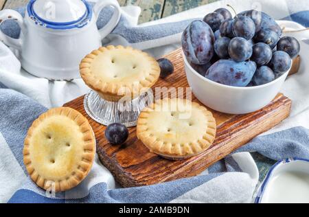 Trois petits gâteaux clos avec prunes et un crémier et bol à sucre dans un style vintage Banque D'Images