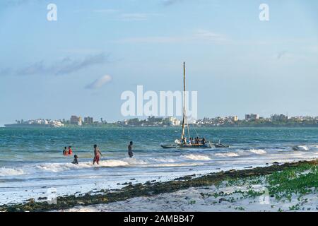 Un bateau à voile traditionnel en bois dow avec des passagers qui naviguent sur l'océan Indien avec Mombasa en arrière-plan, Kenya Banque D'Images