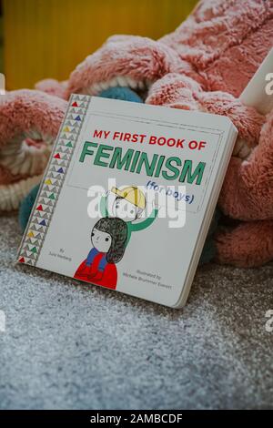 Jeune enfant lisant « Mon premier livre du féminisme (pour les garçons) par Julie Merberg Banque D'Images