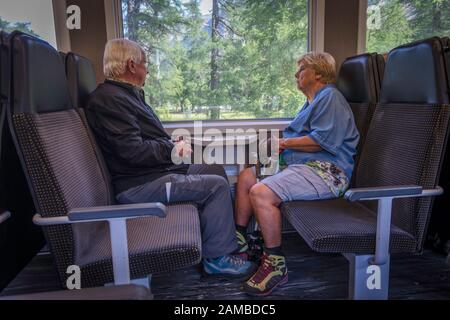 Un couple est assis sur le train RHB qui relie St Moritz en Suisse à Tirano en Italie, traversant le col de la Bernina. Banque D'Images