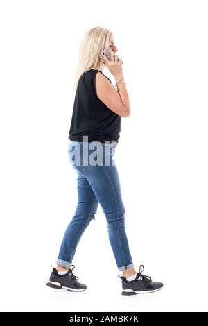 Vue latérale d'une femme d'âge moyen très occupée qui marche à la hâte parle sur le téléphone portable. Longueur totale du corps isolée sur fond blanc. Banque D'Images