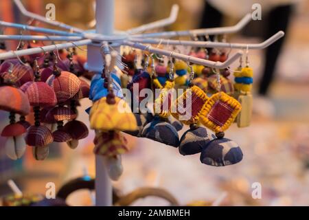 Les boucles d'oreilles traditionnelles indiennes à base de main avec fond flou sont exposées dans une boutique de rue à la vente. Artisanat et art indiens Banque D'Images