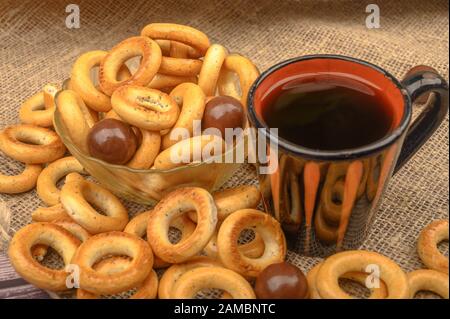 Bagels, petits chocolats, une tasse de thé et un tissu de fabrication locale sur un fond de bois close-up Banque D'Images