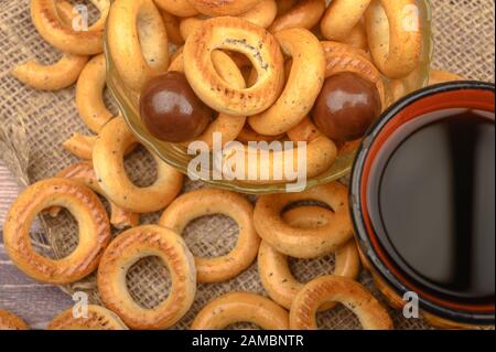 Bagels, petits chocolats, une tasse de thé et un tissu de fabrication locale sur un fond de bois close-up Banque D'Images