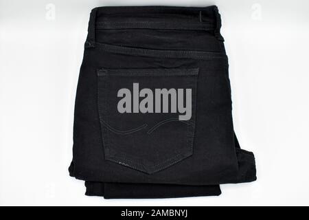 Jean skinny noir plié sur fond blanc Banque D'Images