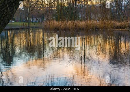 Étang du village dans un quartier historique de Berlin, Allemagne. Vous pouvez voir un ciel bleu et orange brillant le soir qui se reflète dans l'eau. Banque D'Images