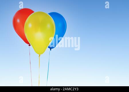 Ballons colorés pour l'anniversaire et les célébrations isolés au ciel bleu Banque D'Images