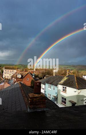 Double arc-en-ciel sur des maisons contre un ciel gris orageux. Axminster, Royaume-Uni Banque D'Images