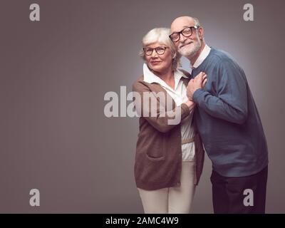 Portrait d'un couple senior doux embrassant , vêtements décontractés, fond gris Banque D'Images