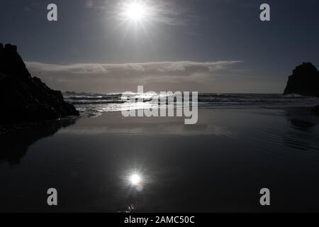 Soleil réfléchissant sur le sable humide sur la plage de Kynance Cove, Cornwall Banque D'Images