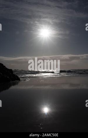 Soleil réfléchissant sur le sable humide sur la plage de Kynance Cove, Cornwall Banque D'Images