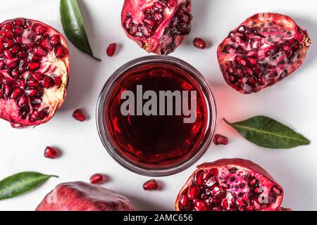 Vue de dessus du jus de grenade dans un verre avec des fruits frais de grenade sur une table en marbre. Vue de dessus. Concept de boisson saine Banque D'Images