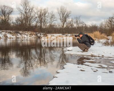 Homme faisant les photos sur la rive de la Vistule pendant l'hiver. Pologne. Natura 2000 Banque D'Images
