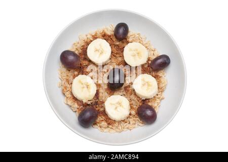 Petit déjeuner sain à faible teneur en gras de flocons d'avoine chauds, de tranches de bananes et de bleuets dans un bol blanc Banque D'Images