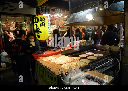 Étals de restauration vendant des crêpes salées de juin à la Corée dans le marché alimentaire animé de Tsuruhashi, Osaka. Banque D'Images