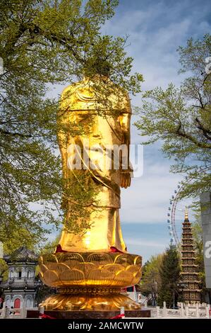 Une statue de bouddha sur pied d'or sur un ciel bleu ensoleillé de printemps au temple de Jile à Harbin Chine. Banque D'Images