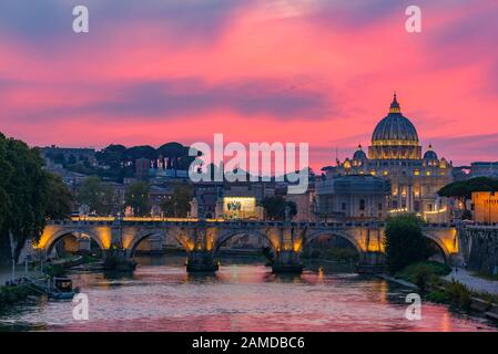 Vue sur le coucher du soleil sur la basilique Saint-Pierre, le Ponte Sant'Angelo et la rivière Tiber à Rome, en Italie Banque D'Images