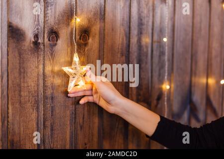 Woman's hand touching décoration de Noël étoile brillante sur le mur en bois. Concept de vacances de Noël Banque D'Images