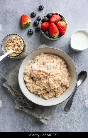 Porridge de flocons d'avoine dans un bol vue sur le dessus de table servi avec des fruits frais bleuets et des fraises. Un petit déjeuner sain Banque D'Images