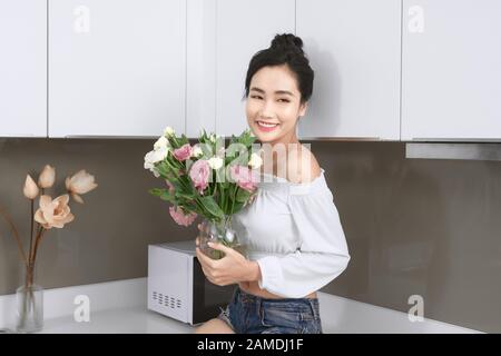 Portrait de la jeune femme asiatique avec fleurs dans la cuisine. Banque D'Images